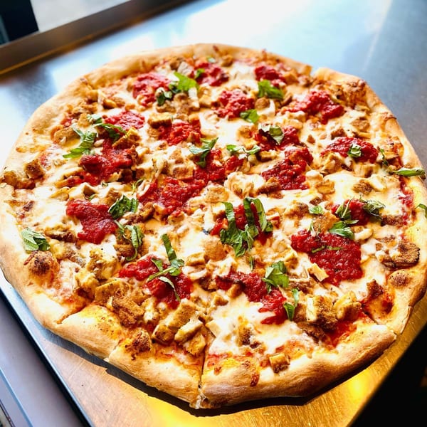 A Spaghettini Pizza Trattoria pizza with red sauce, mozzarella, chicken, and fresh basil.