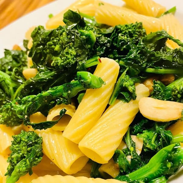 Close-up of Spaghettini's rigatoni pasta with vibrant green broccoli rabe and garlic.