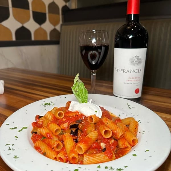 Rigatoni pasta with red sauce, ricotta, and basil, served with red wine at Spaghettini.